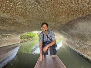 A Polynesian Cultural Center guide crouches on a canoe as it passes beneath a low bridge along the waterway.