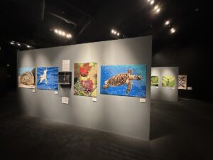 A gallery wall at Bishop Museum displays LEGO brick artwork of Hawaiian wildlife and natural scenes, including a sea turtle and native birds.