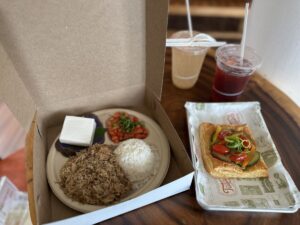 A Hawaiian lunch from Tūtū’s Place by Highway Inn, served with rice, traditional sides, a savoury pastry, and two drinks.