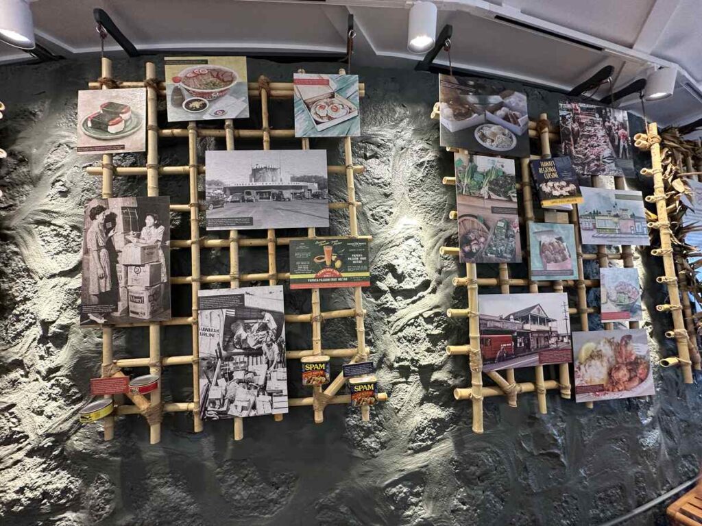 A history wall at Tūtū’s Place by Highway Inn displays photographs, menus, packaging, and stories from the restaurant’s family legacy.