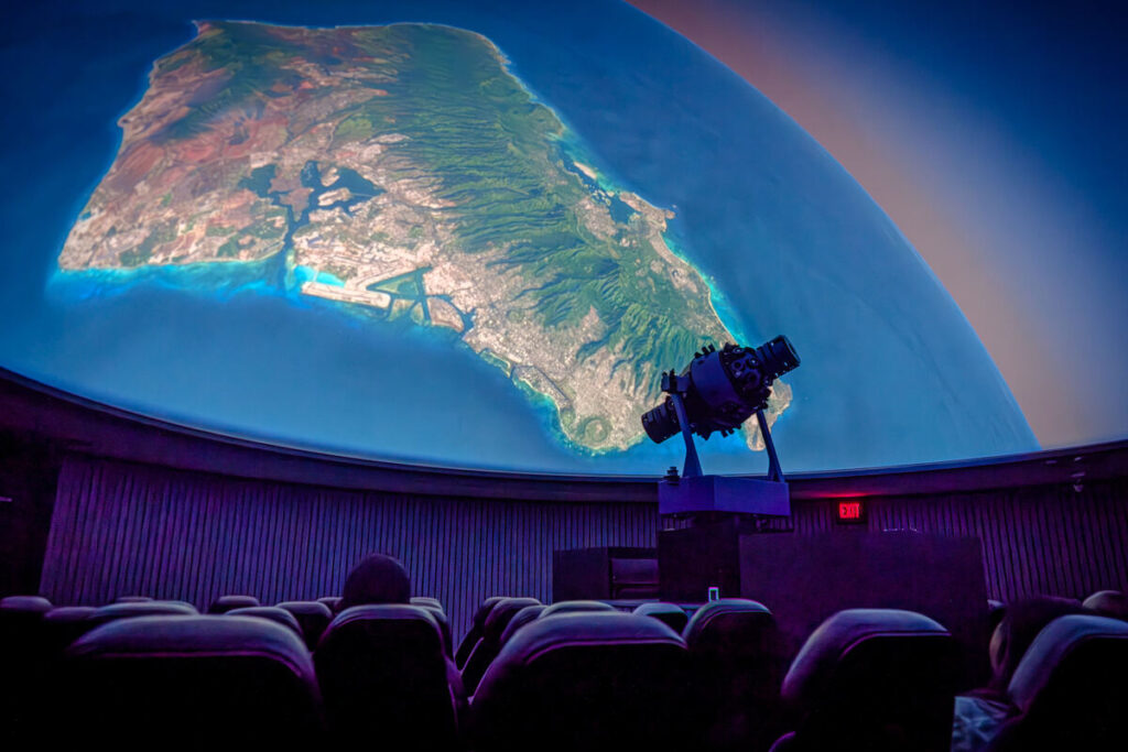 Inside Bishop Museum’s J. Watumull Planetarium, an image of Oʻahu is projected across the domed ceiling.