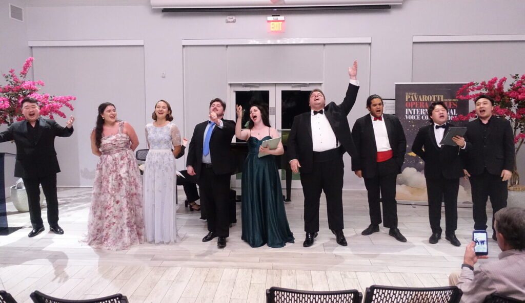 Opera singers performing together indoors at the Pavarotti International Voice Competition.