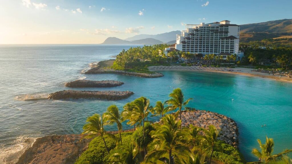 Aerial view of Four Seasons Resort Oahu at Ko Olina beside turquoise lagoons, palm trees, and the western Oʻahu coastline.