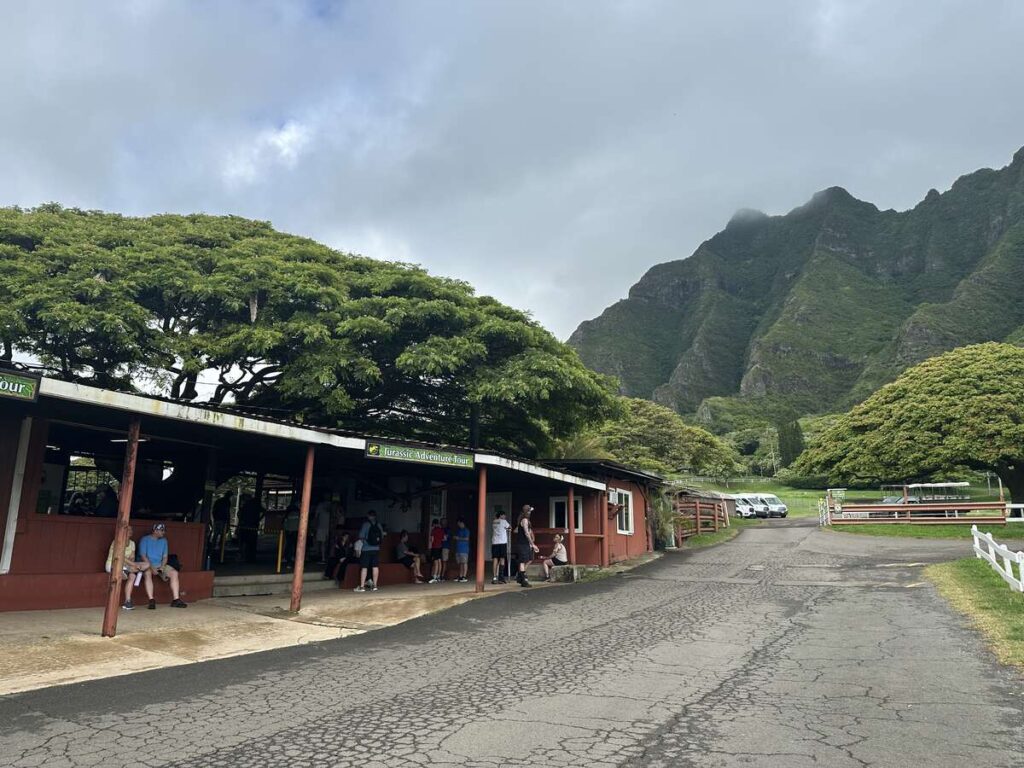 Jurassic Adventure Tour depot at Kualoa Ranch with mountains and tour vehicles nearby.