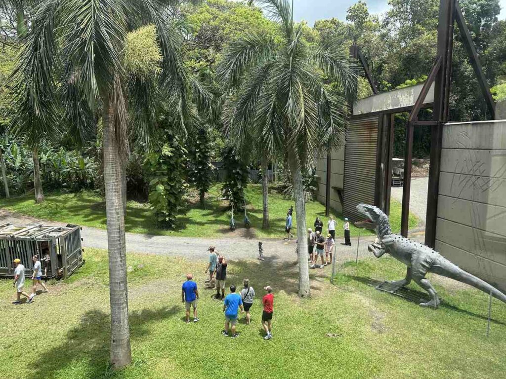 Overhead view of visitors near a dinosaur figure and Jurassic World set at Kualoa Ranch.