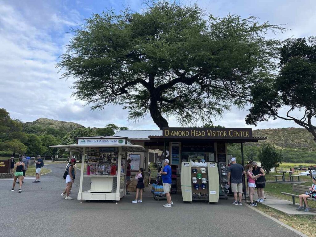 Diamond Head Visitor Center kiosk with travellers gathered beneath a large shade tree.