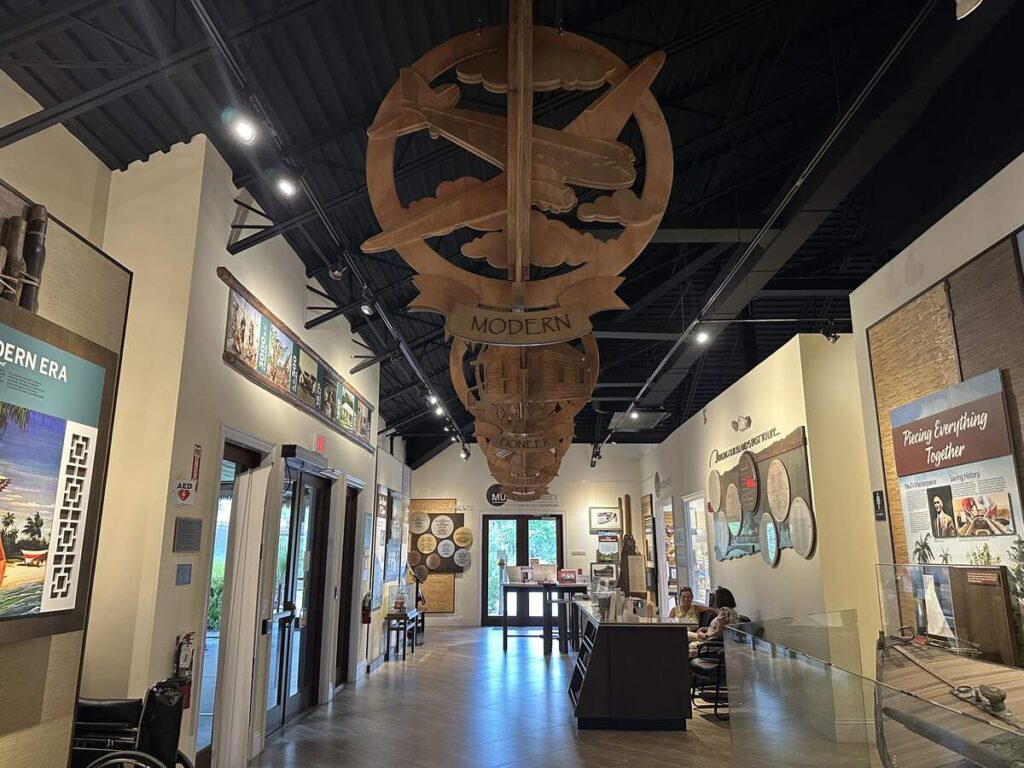 Main gallery at the Marco Island Historical Museum with exhibits, wall panels, display cases, and a suspended timeline sculpture.
