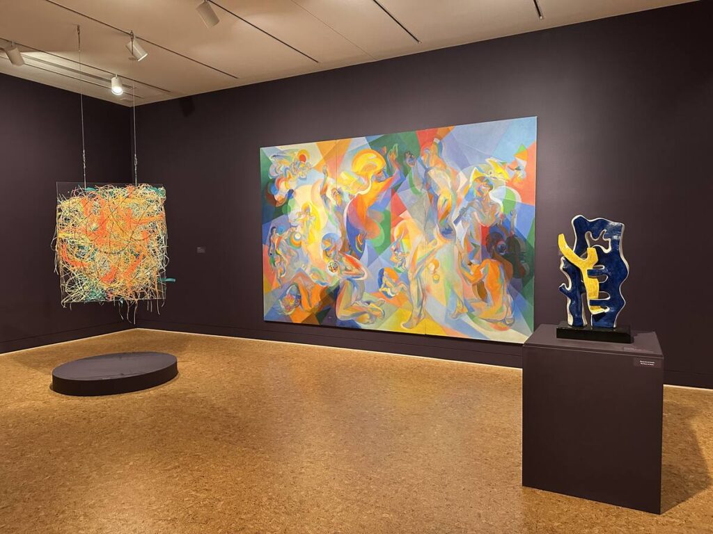 Gallery at The Baker Museum with a colourful hanging installation, large abstract painting, and sculptural work on a pedestal.