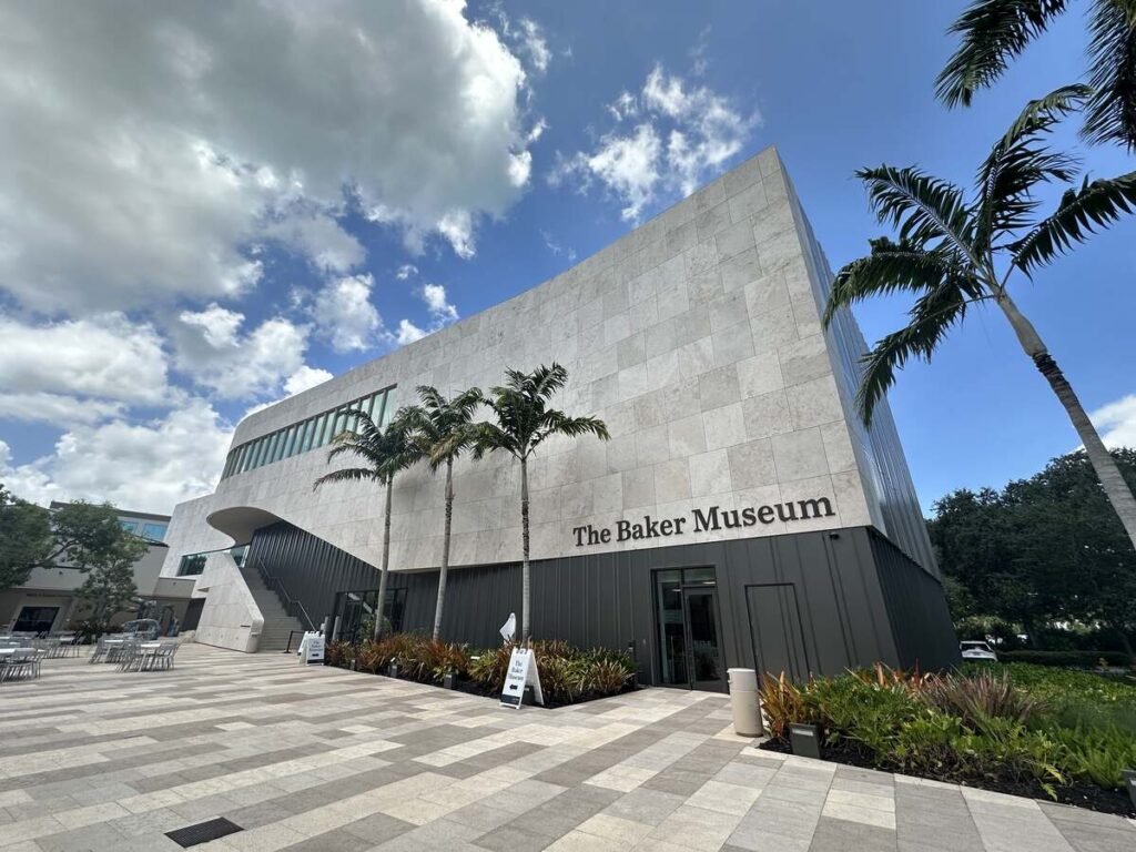 Exterior of The Baker Museum at Artis—Naples, with palm trees, pale stone walls, and a bright blue sky.
