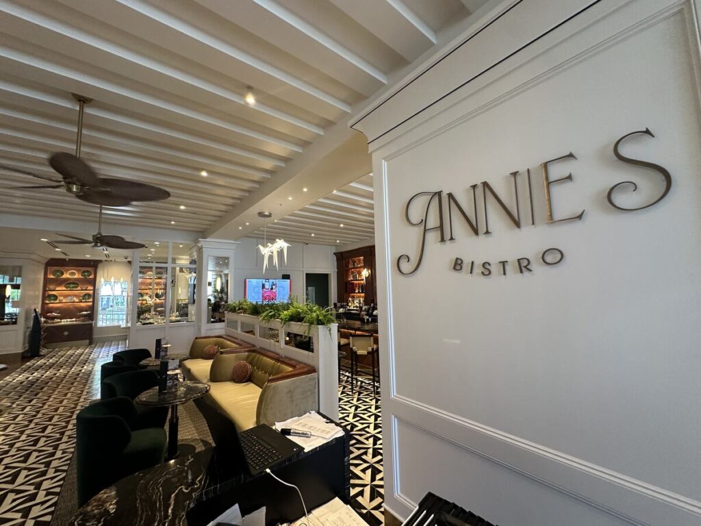 The entrance area of Annie’s Bistro in Naples, with the restaurant’s name displayed on a white wall beside a stylish lounge and bar.