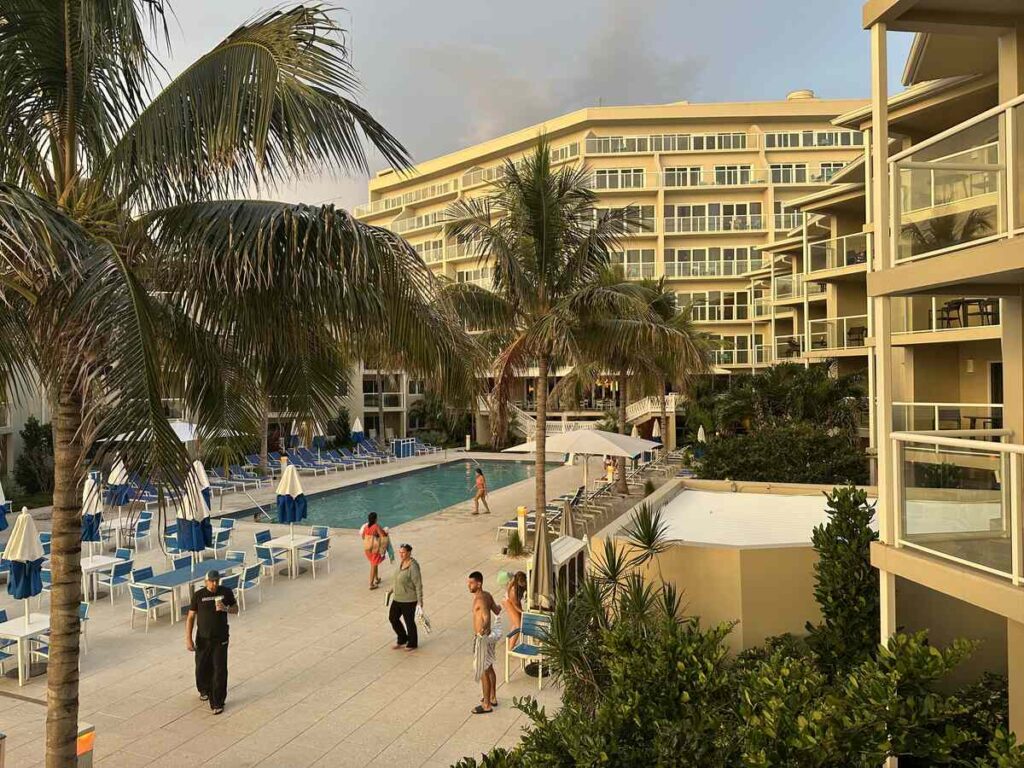 Pool area at Edgewater Beach Hotel in Naples, with palm trees, lounge chairs, umbrellas, and surrounding suites.