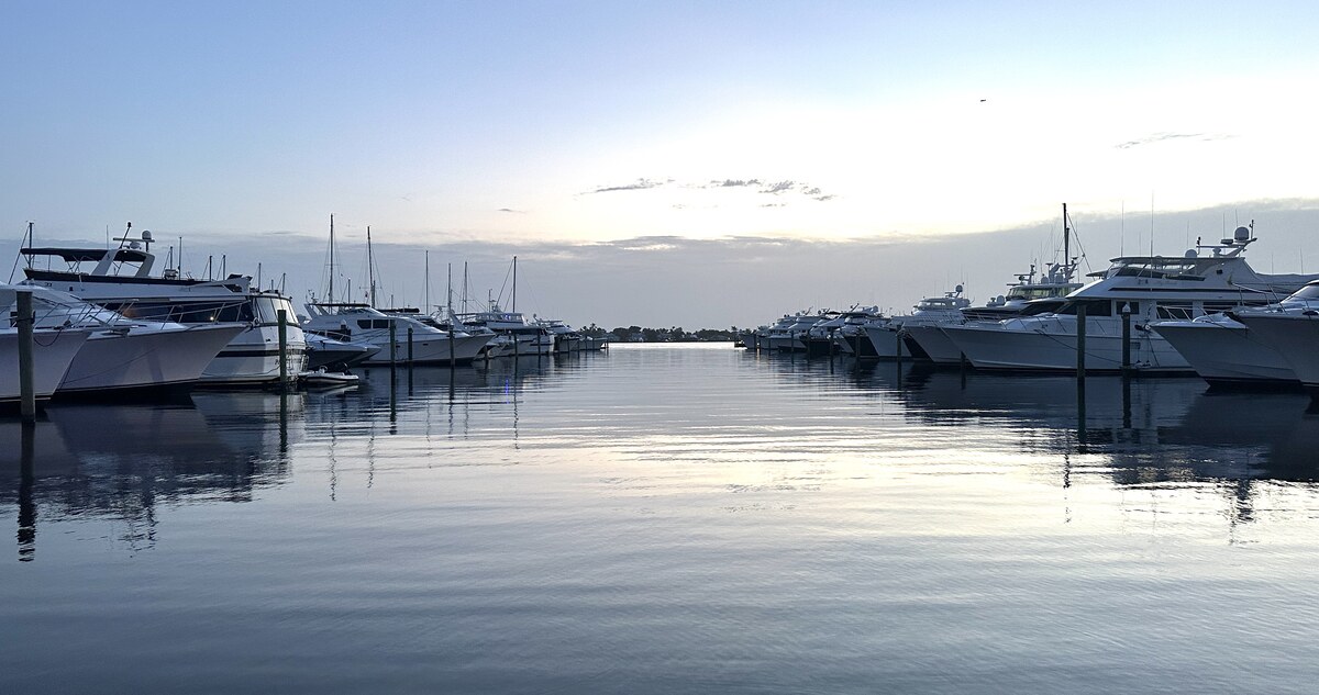Calm marina water at dusk in Stuart, Florida, with boats docked on both sides and reflections on the water.