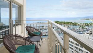 Balcony with two chairs overlooking the marina, ocean, and coastline near Waikīkī.