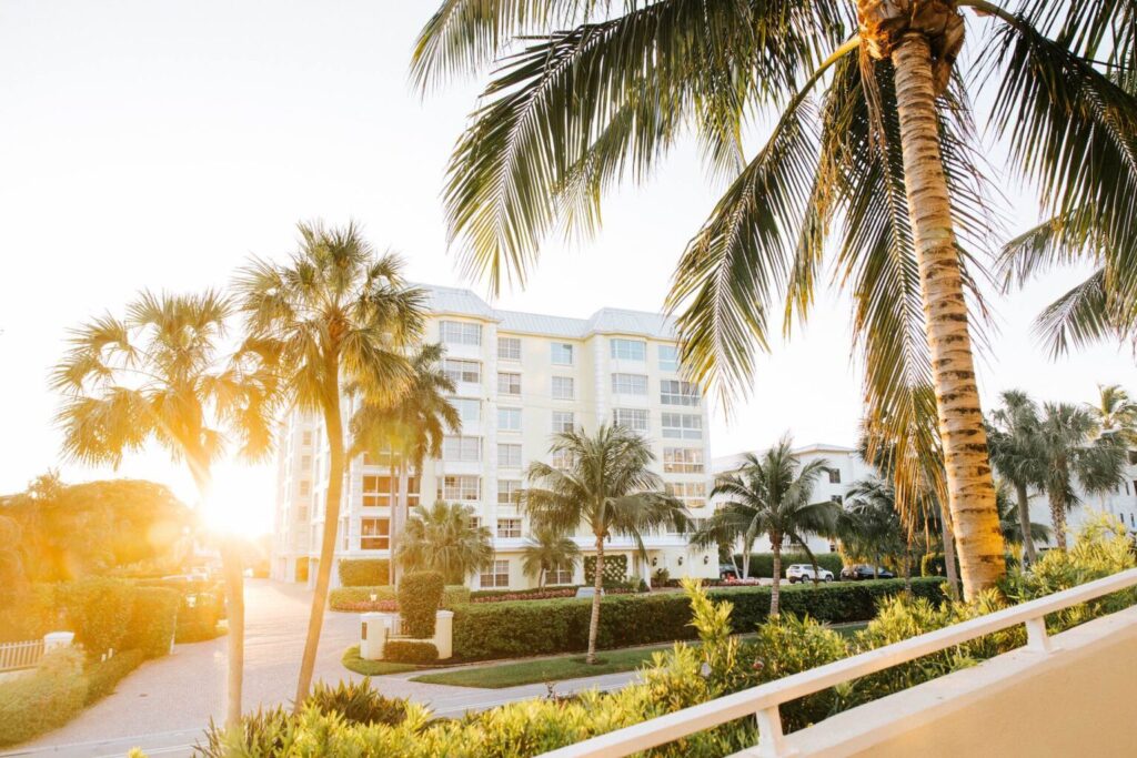 Exterior of Edgewater Beach Hotel in Naples, Florida, framed by palm trees and warm sunlight.