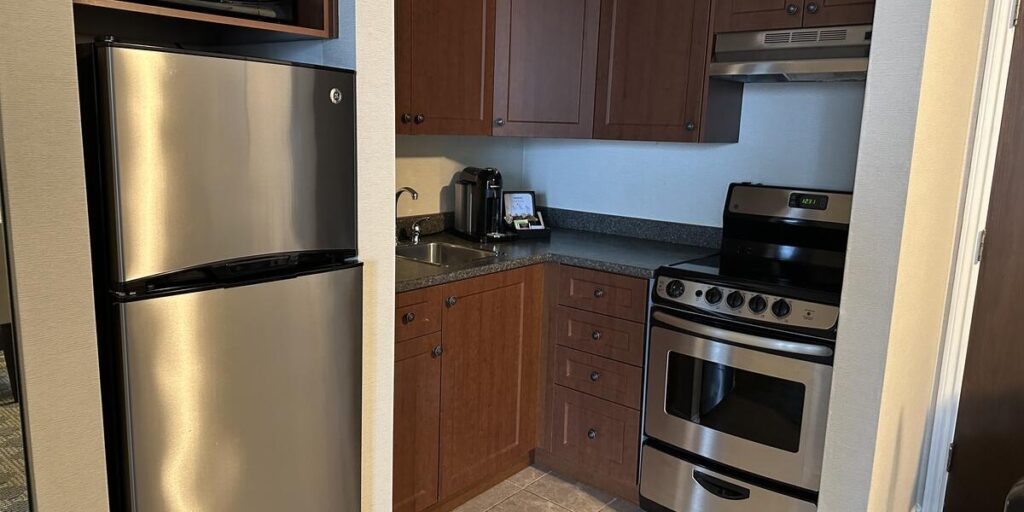 Full kitchen with refrigerator, stove, microwave and cabinets in a Chateau Victoria suite.