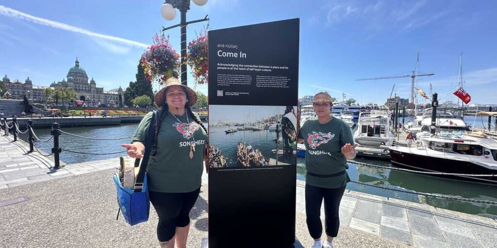 Songhees Tours guides beside an interpretive sign on Victoria’s Inner Harbour.