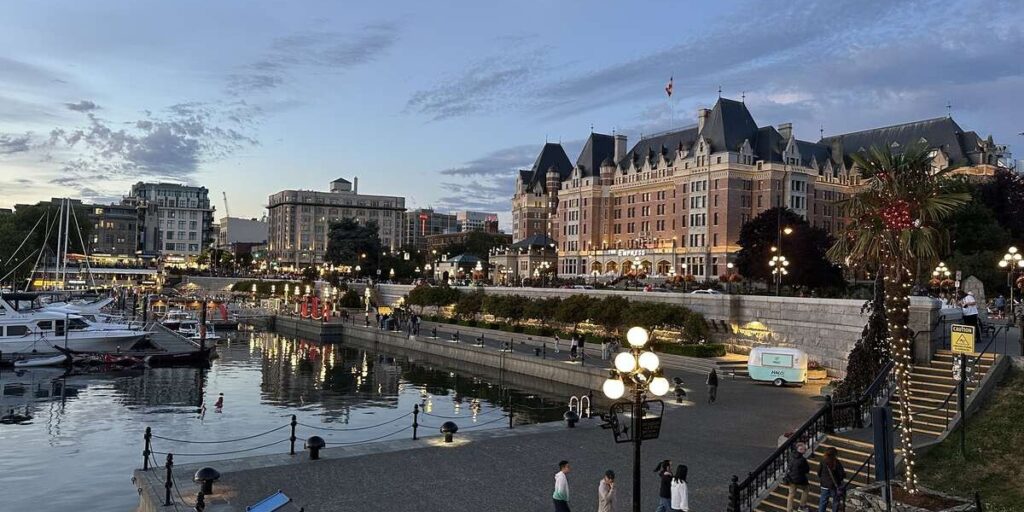 Fairmont Empress illuminated at dusk above Victoria’s Inner Harbour waterfront.